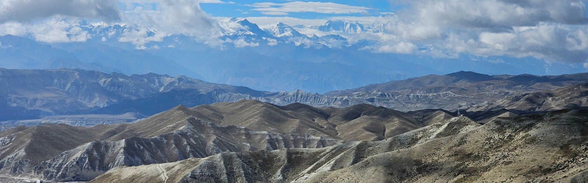 Paysage désertique du Haut Mustang avec falaises rouges et sommets enneigés de l'Annapurna en arrière-plan