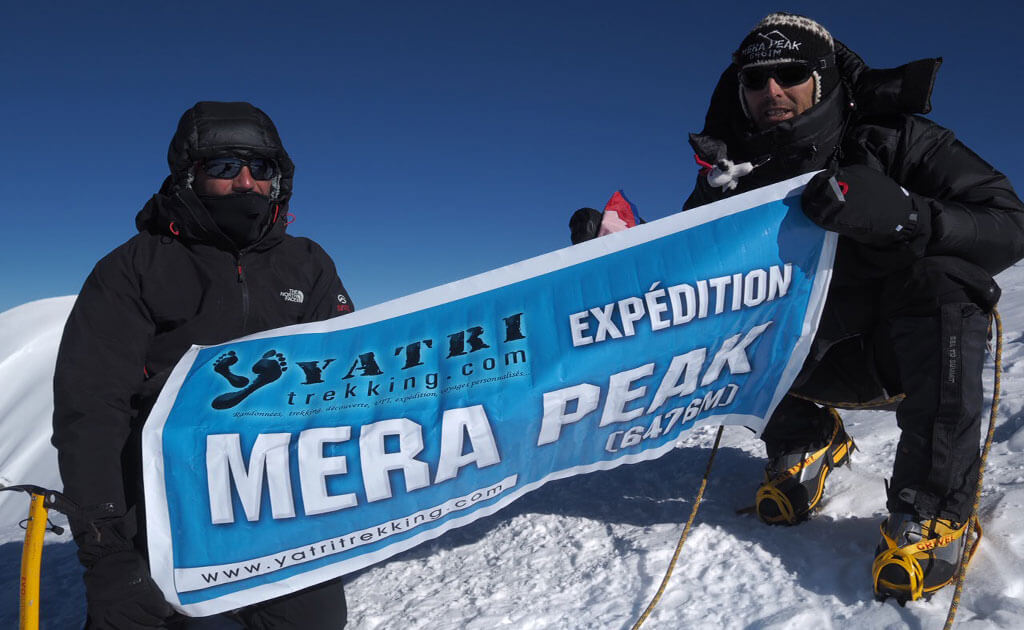 Alpinistes progressant dans la vallée de Hinku vers le sommet du Mera Peak sous un ciel bleu profond