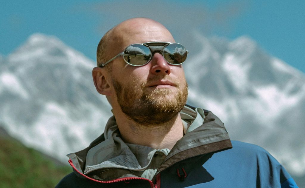 Trekkeur portant des lunettes de soleil polarisées avec les sommets enneigés derrière